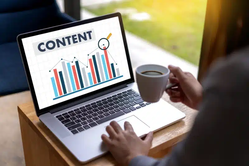 Person viewing content analytics on laptop with coffee