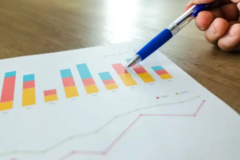Hand pointing at colorful bar graph on paper