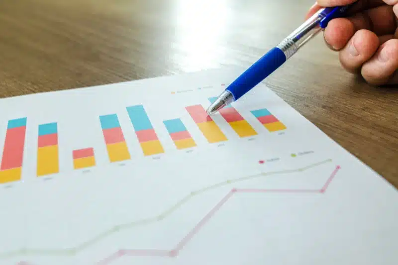 Hand pointing at colorful bar graph on paper