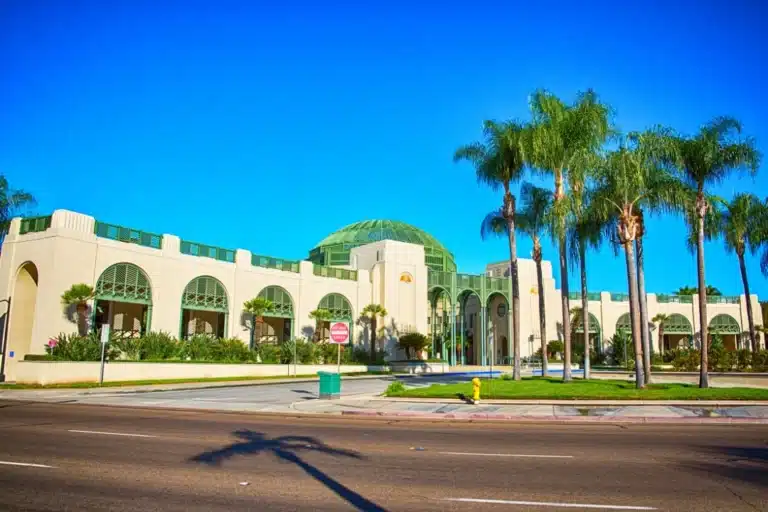 Exterior view of the Escondido Civic Center with iconic green arches, palm trees, and a clear blue sky.