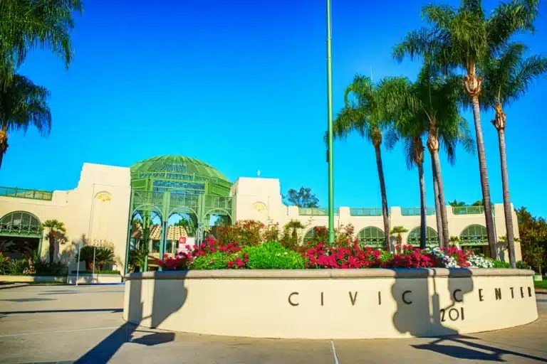 Front view of Escondido Civic Center with domed architecture, palm trees, and landscaped garden under bright sunlight.