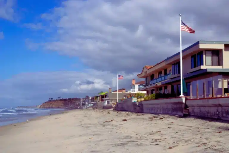 Beachfront homes in Del Mar overlooking the ocean with American flags and cloudy blue sky